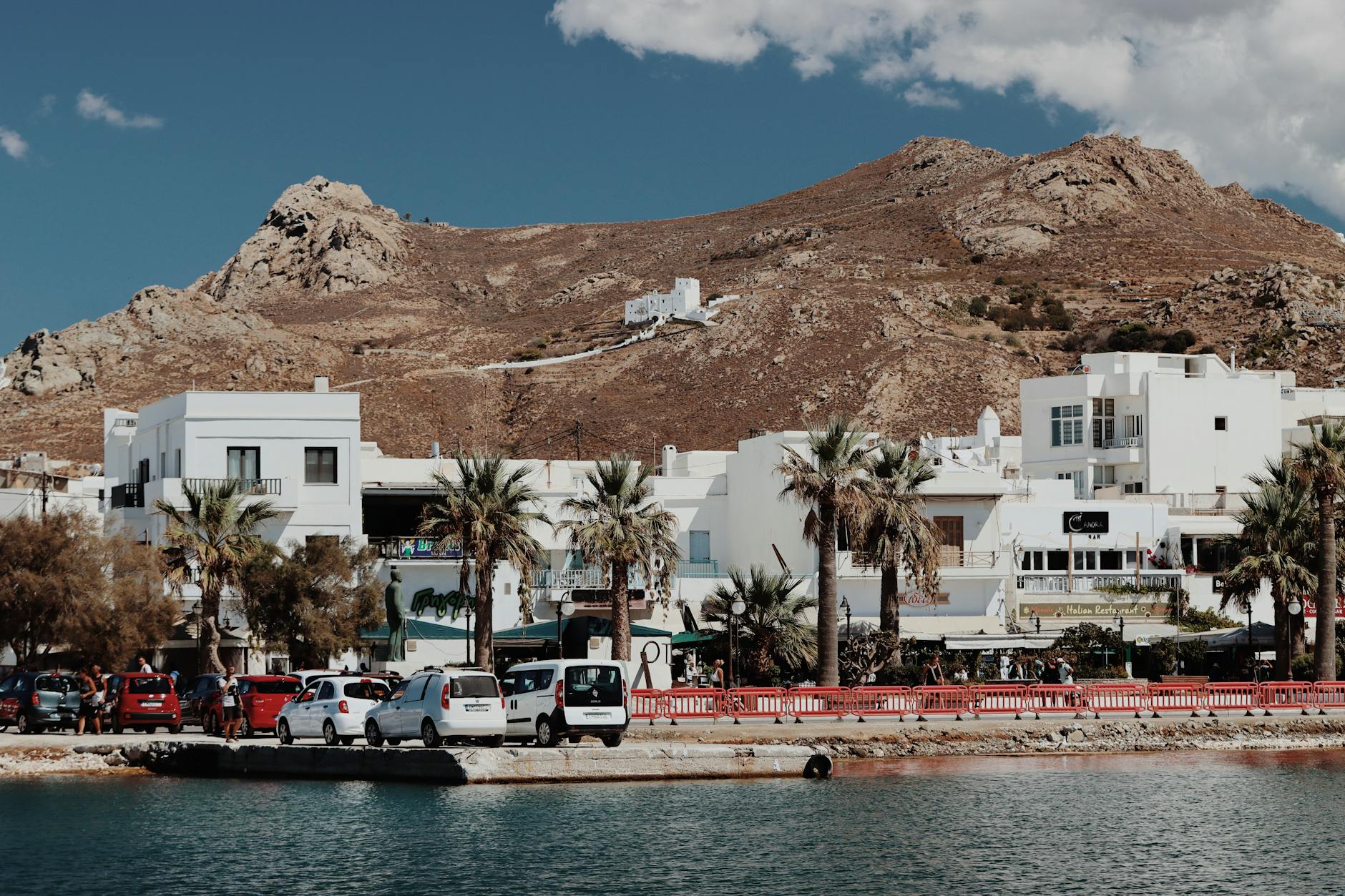 greece car rental costs - scenic Mediterranean road with parked rental cars